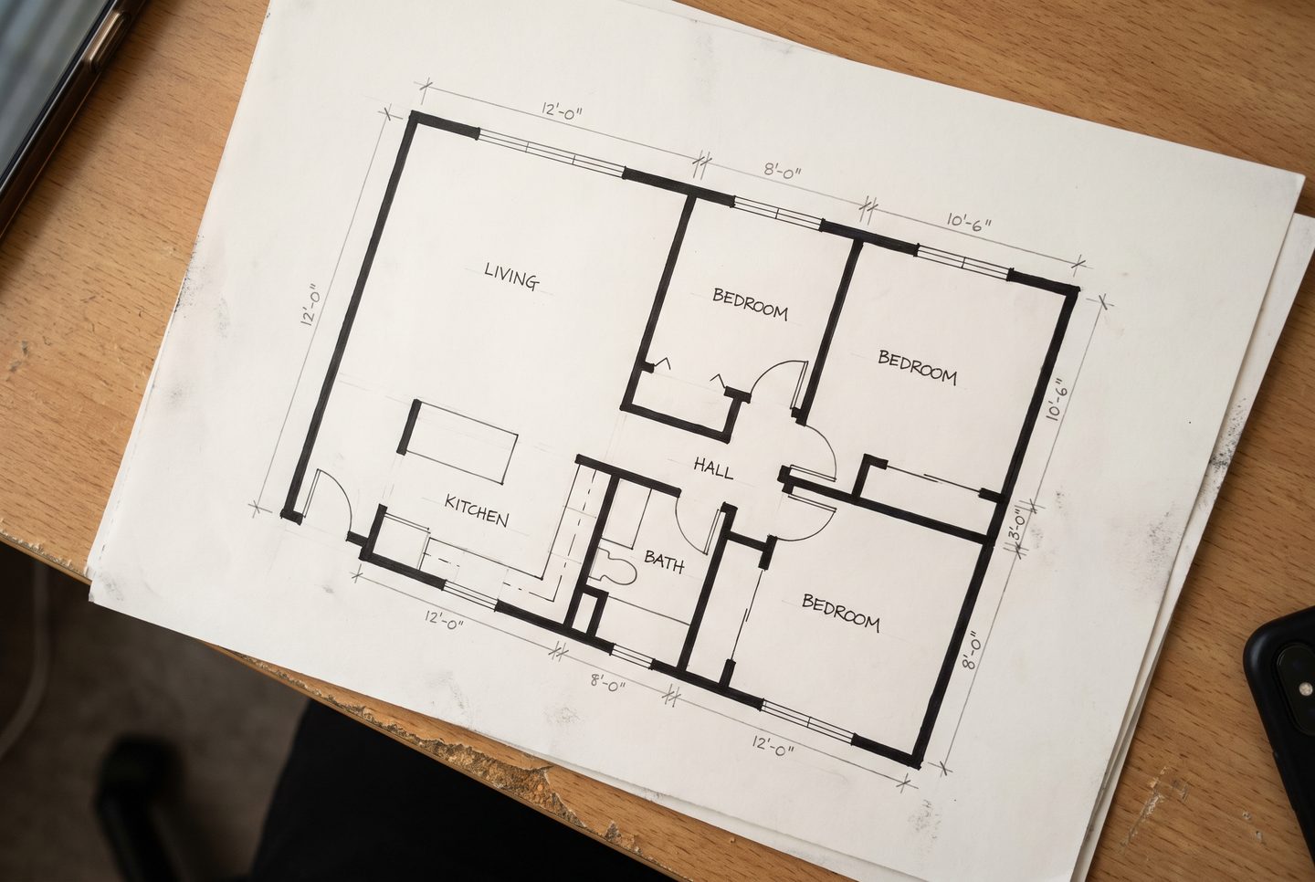 A hand-drawn two-bedroom floor plan on paper, photographed on a desk.