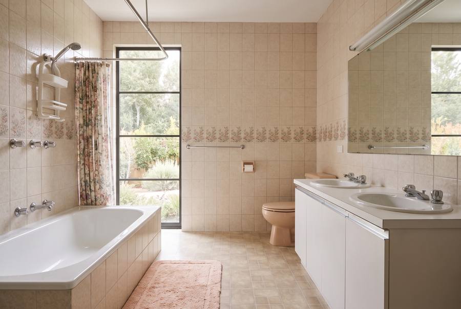 The bathroom as it was: beige tiles with a border strip, a built-in bath with a shower curtain, a laminate vanity.