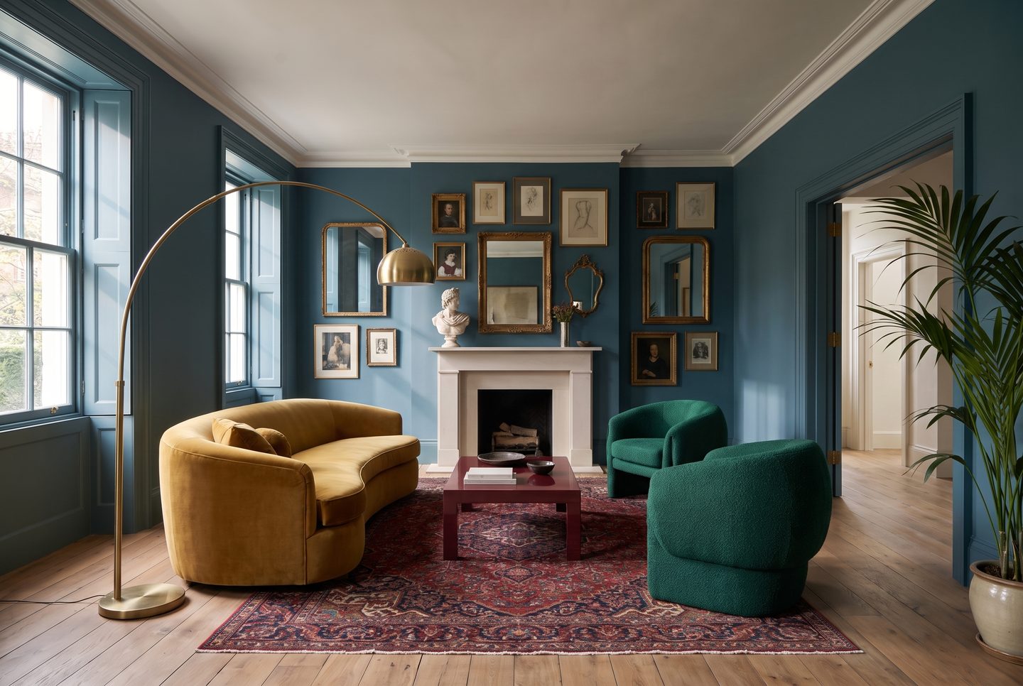 The same room taken somewhere you would not have asked for: teal walls, a mustard velvet sofa, emerald armchairs, a gallery wall around the fireplace, a palm by the door.