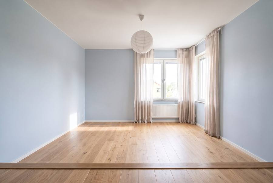 The same child's room emptied: bare floor and walls, the window and radiator untouched.